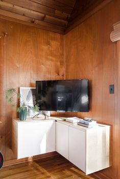 a flat screen tv sitting on top of a white cabinet next to a wooden wall