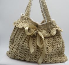 a crocheted purse with a bow on the front and side, sitting on a white surface