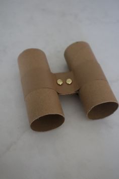 a pair of binoculars sitting on top of a white table next to a brown paper tube