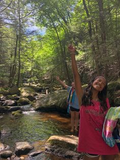 two girls are standing in the water with their arms up and one girl is raising her hand