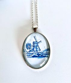 Delft blue necklace, Dutch necklace, Gift for Oma, Glass cameo necklace, Dutch Jewelry, Blue pendant necklace, Gift for women This beautiful necklace has a Dutch Windmill in the country, remembering the Dutch country scenes in the Netherlands..    the chain is a stainless steel silver colour cable or ball chain.  the lengths: - 24 inches cable chain - 30 inches ball chain the cabochon measures 30mm by 40mm and is silver colour.  a perfect gift for mom, for sisters, for a birthday.    this neckla Handmade Oval Glass Necklace, Vintage Glass Necklace Nickel Free, Vintage Glass Nickel-free Necklace, Vintage Nickel-free Glass Necklace, Glass Pendant Necklace With Lobster Clasp, Glass Pendant Necklace For Gifts, Glass Necklace With Large Pendant As Gift, Glass Pendant Necklaces For Gifts, Necklace With Large Glass Pendant As Gift