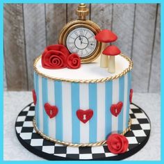 a blue and white striped cake with red roses on the top is topped with a clock