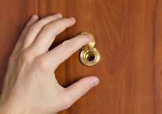 a person's hand on top of a wooden table with a gold door knob