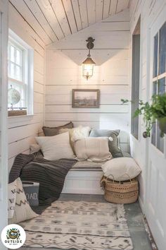 a small room with white walls and wood flooring is decorated in neutral tones, such as the pillows on the window sill