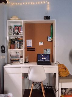 a laptop computer sitting on top of a white desk next to a book shelf filled with books