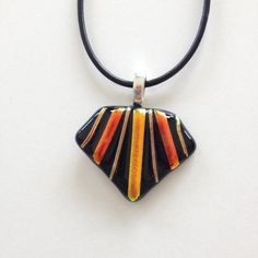 a black and orange striped pendant hangs from a leather cord