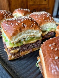 several hamburgers with cheese and lettuce sitting on a tray next to each other