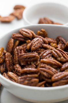 a white bowl filled with pecans on top of a table