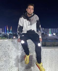 a man sitting on top of a cement wall