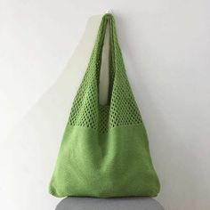 a green bag hanging on the wall next to a gray chair with a grey cushion