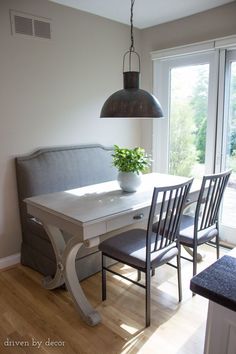 a dining room table with four chairs and a plant in the vase on top of it