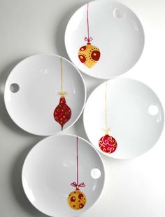 three white plates with ornaments hanging from them