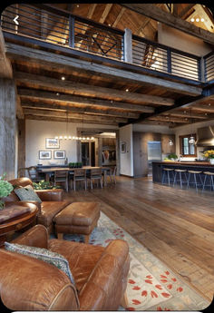 a large open floor plan living room and kitchen area with wood floors, high ceilings, and exposed beams