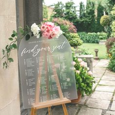 a sign that says find your seat in front of some flowers and greenery on the side of a building