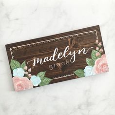 a wooden name plate with flowers on it and the word naddelyn grace written in white