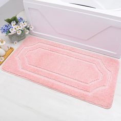 a bathroom rug that is next to a bathtub and sink with flowers on the floor