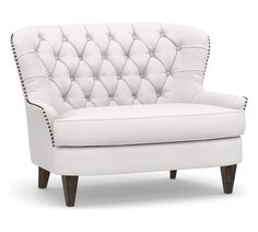 a white leather chair with studding on the armrests and back rests in front of a white background