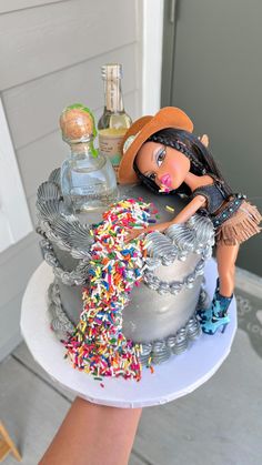 there is a cake that has sprinkles on it and a doll next to it