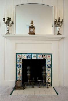 a fireplace with a mirror above it and two candles on the mantels next to it