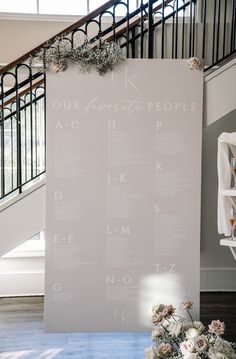 a wedding seating chart with flowers and greenery in front of the stairs at their reception