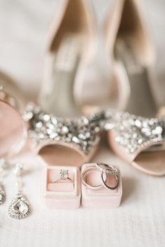 a pair of shoes, ring and earrings on a white table cloth next to wedding rings