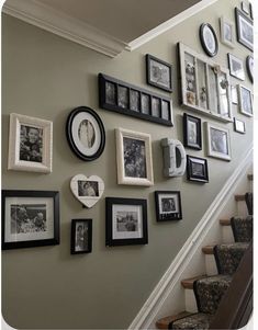 a staircase with many pictures on the wall and framed photos hanging up against the wall