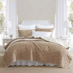 the bed is made with white linens and has an orange flower pattern on it