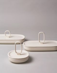 three white plates with rings on them sitting next to each other in front of a gray background