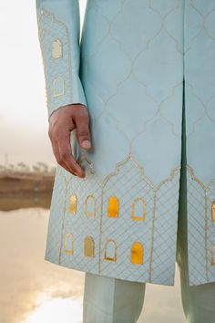 Powder blue full sleeve sherwani hand embroidered with gold khidki applique motifs and embellished with cutpipe work. Paired with pant pyjama.
Components: 2
Pattern: Embroidery, Embellished
Type Of Work: Thread, cutpipe
Neckline: Mandarin collar
Sleeve Type: Full sleeves
Fabric: Sherwani: Chanderi Silk, Pant Pyjama: Vegan Silk
Color: Blue
Other Details: 
Pleated collar
Disclaimer: The fabrics used, are handwoven, hence may have impurities or slubs/variation in the weave that beautifies the look Nav Durga, Blue Sherwani, Indian Groom Wear, Fashion Models Men, Men Kurta, Mens Fashion Illustration, Wedding Outfit Men, Designer Suits For Men, Indian Groom