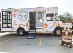 a food truck parked in a parking lot with flowers painted on it's side