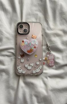 an iphone case with a heart shaped brooch and keychain attached to it