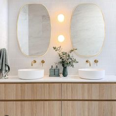 two white sinks sitting next to each other on top of a wooden cabinet in a bathroom