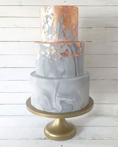 a three tiered cake with gold and silver decorations