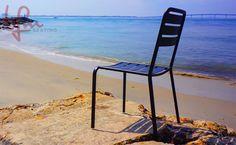 a chair sitting on top of a beach next to the ocean