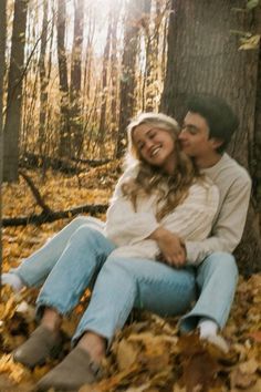 a man and woman are sitting in the leaves