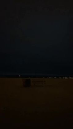 a blurry photo of a bench in the dark by the beach at night time