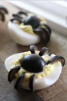 deviled eggs with black and white toppings on a cutting board