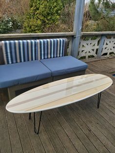 a white surfboard sitting on top of a wooden floor next to a blue couch