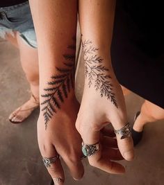 two people holding hands with tattoos on their wrists and fingers, both showing the same tattoo design