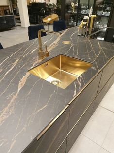 a kitchen with marble counter tops and gold faucets