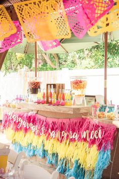 an outdoor party with colorful streamers and tassels hanging from the ceiling,