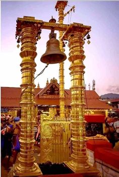 an elaborate golden structure with bells and people around it