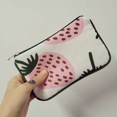 a person holding up a pink and black purse with pineapples on it's side