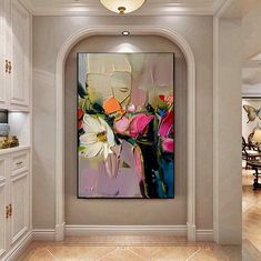 a large painting hanging on the wall in a room with white cabinets and marble flooring