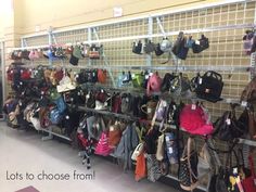 there are many purses and handbags hanging on the wall in this store,