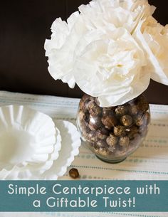 a vase filled with white flowers sitting on top of a table next to paper plates