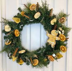 a wreath with oranges, cinnamon sticks and ginger slices hanging on the front door