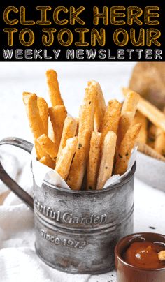 a bucket filled with french fries next to dipping sauce