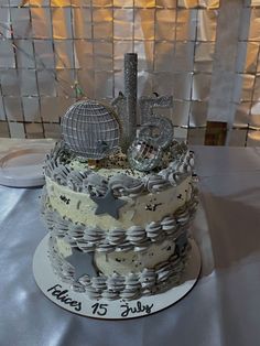 a 50th birthday cake with silver decorations and stars on the top is sitting on a table