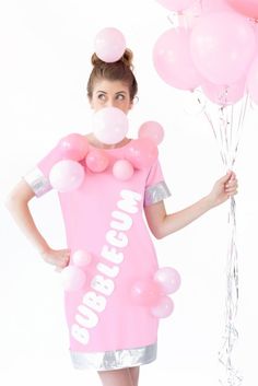 a woman in a pink dress is holding balloons and wearing a bubblegum t - shirt